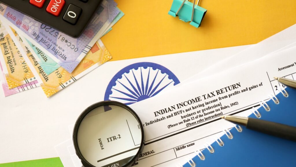 Indian Income Tax Return form with a magnifying glass, calculator, and currency on a yellow surface, symbolizing financial planning and considerations for home construction contractors and home construction in Bangalore