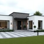 Modern white single-story house with flat roofs, featuring large windows and dark stone accents. The front has a small porch and a potted shrub. Black and white exterior lamps line the patterned pavement. A patch of green lawn in the foreground. Cloudy sky backdrop.